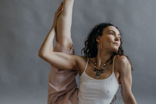 Person performing a gentle stretching yoga pose in a calm studio.